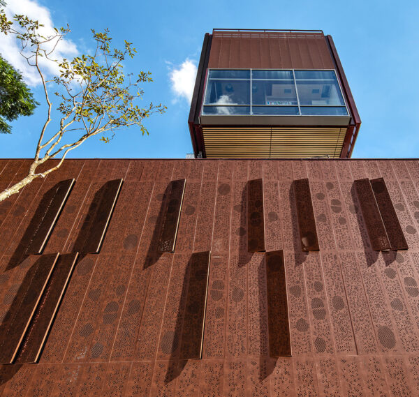 Imagem ilustrativa de painéis perfurados e brises metálicos aplicados em arquitetura moderna, com foco em design funcional e controle térmico.